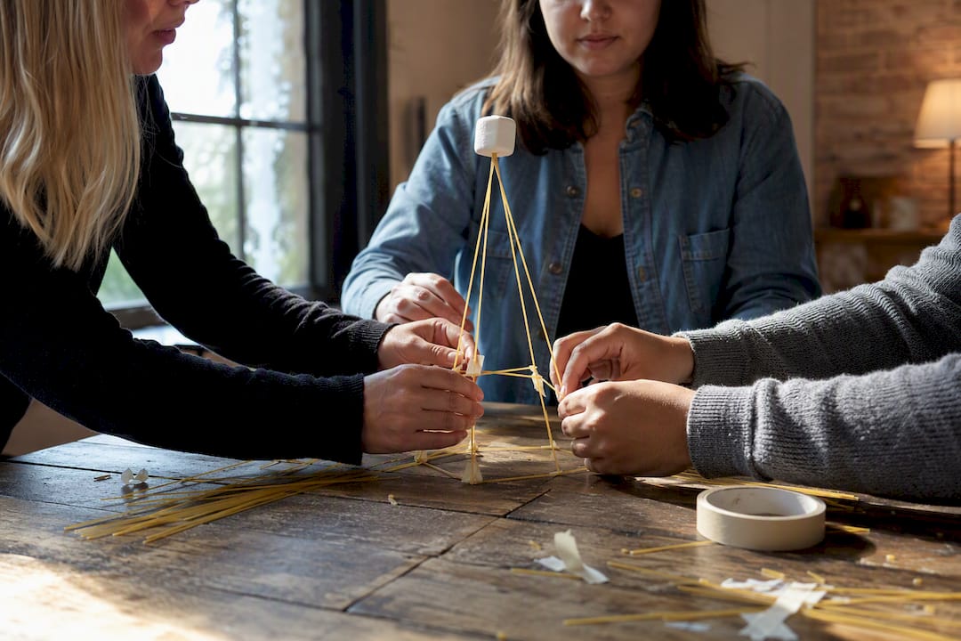 Hands building marshmallow challenge structure