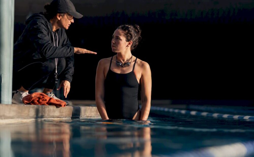 Swimmer listening to coach beside pool