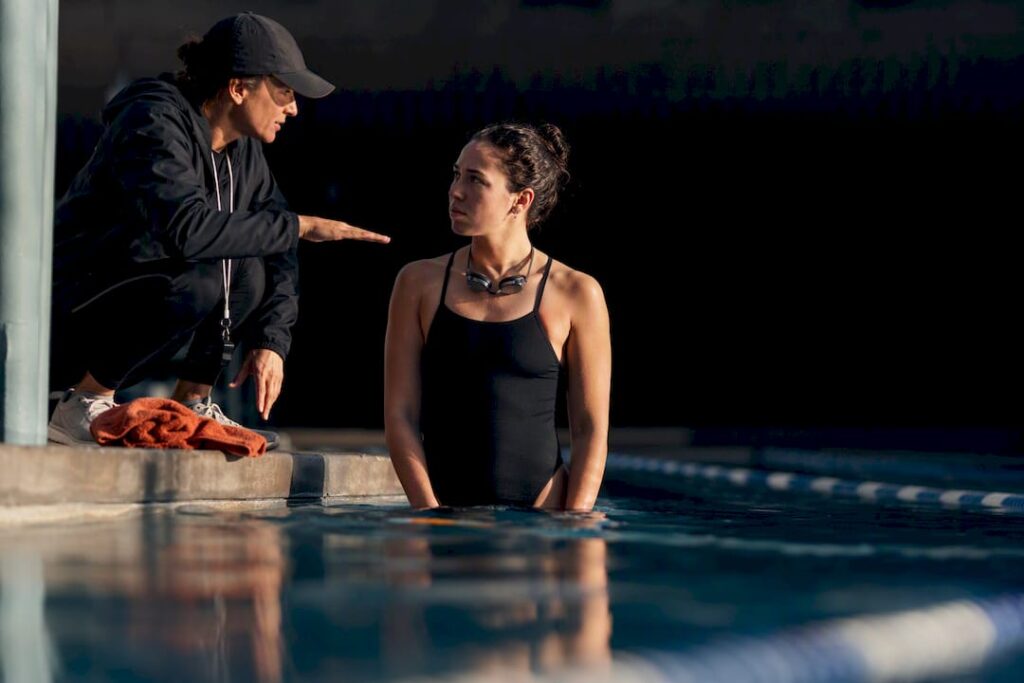 Swimmer listening to coach beside pool