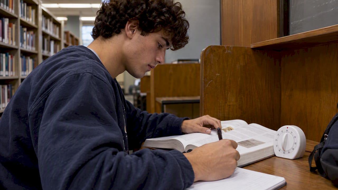 Student-athlete setting a timer beside a textbook