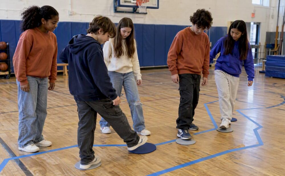Students collaborating across a taped gym river