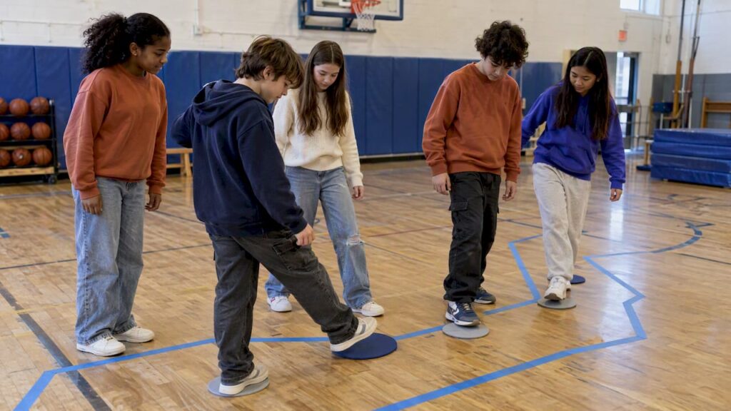 Students collaborating across a taped gym river